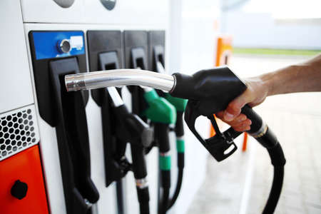 Detail of a hand holding a fuel pump at a station