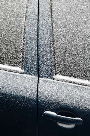 Close-up shot of a car's door covered in snow