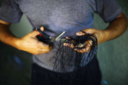 Color detail of a man repairing a fishing net.