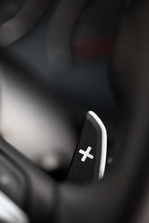 Vertical close up shot of a manual gear changing paddle on a car's steering wheel.