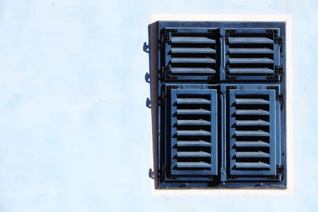 Color shot of a blue wooden window with closed shutters.