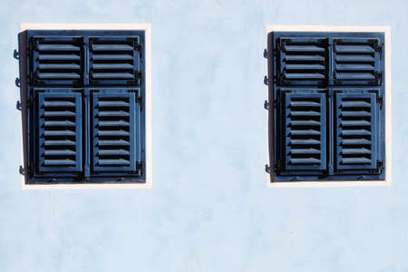 Color shot of a blue wooden window with closed shutters.の写真素材