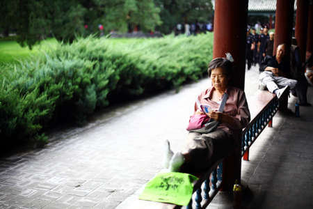 Beijing, China - September 24, 2014: An elderly woman reads a book in a park in Beijing, China.のeditorial素材