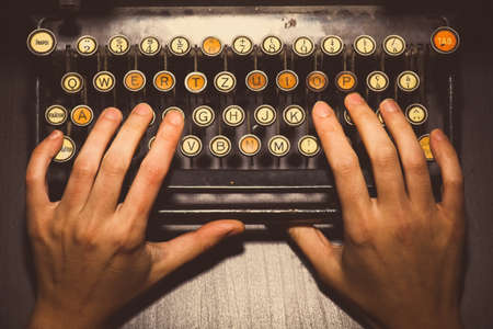 Color horizontal detail of two hands writing on the keyboard of an old typewriter.