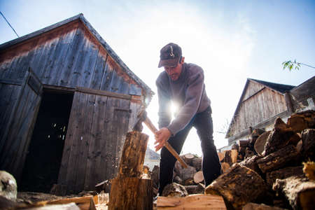 Viscri, Romania - November 7, 2014: Color picture of a man chopping wood in his yard, in the village of Viscri, Romania.のeditorial素材