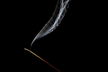 Studio shot of a burning incense on a black background.の写真素材