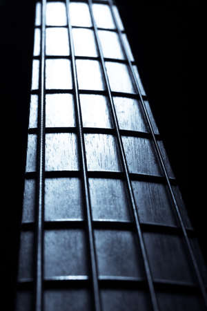 Detail of the fret board of a bass guitar, on a dark background.の写真素材