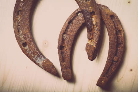 Color shot of two horse shoes on a wooden background.の写真素材