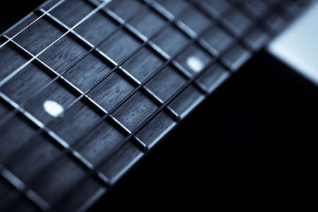 Detail of the fret board of an acoustic guitar, on a dark background.の写真素材