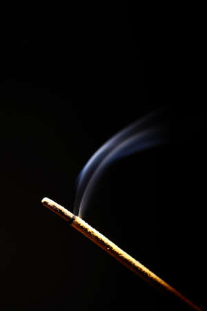 Studio shot of a burning incense on a black background.の写真素材