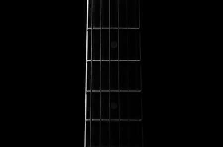 Detail of the fret board of an acoustic guitar, on a dark background.