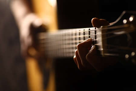 Color detail of hand playing of an old, acoustic guitar.