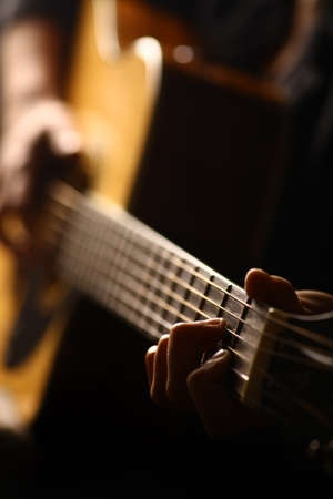 Color detail of hand playing of an old, acoustic guitar.