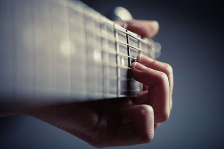 Color detail of hands playing of an old, acoustic guitar.