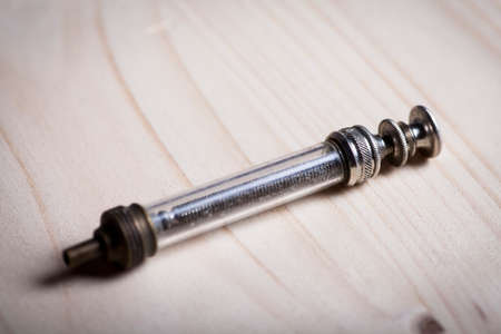 Close-up shot of a vintage syringe on a wooden plank.の写真素材