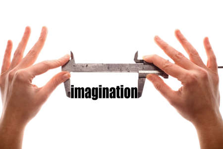 Color horizontal shot of two hands holding a caliper and measuring the word imagination.