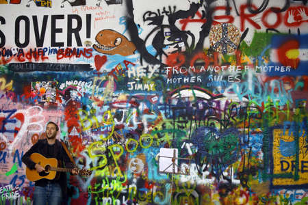 Prague, Czech Republic - June 9, 2015: Color image of a street performer playing the guitar in front of the John Lennon wall in Prague, Czech Republic.のeditorial素材