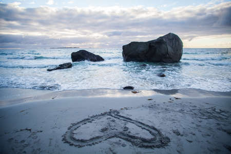 Color image of a beach at dawn with a heart drawn on the sand.の写真素材