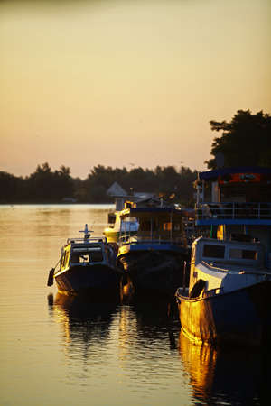 Color image of some ships in a port, at sunrise.