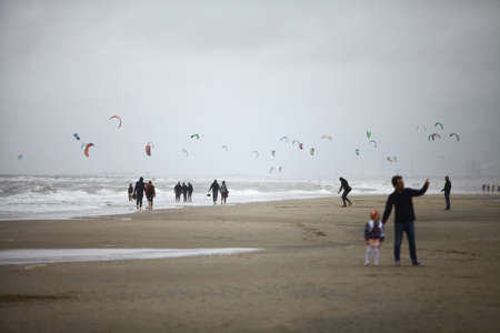 Zanvoort, Netherlands - July 12, 2015: People walk on the beach with kite-surfers, on a cloudy day, in Zanvoort, Netherlands.のeditorial素材