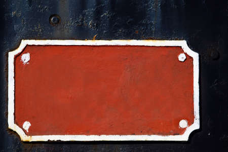 Old blank red metal sign on a dark background.の写真素材