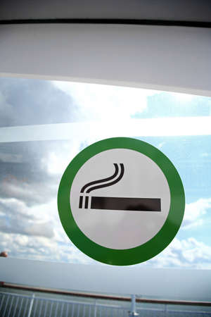 Picture of a sign marking the designated smoking area on a window.の写真素材