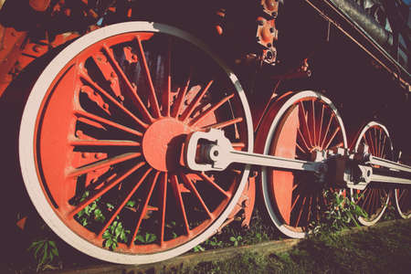 Color image of an abandoned steam locomotive's wheels, with plants growing around them.の写真素材