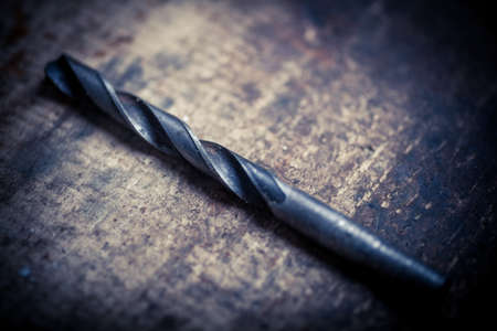 Color image of a drill bit on a wooden plank.