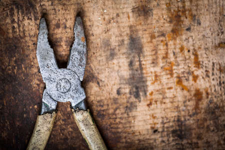 Color image of an pliers on a wooden plank.