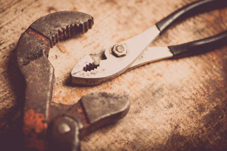 Color image of an adjustable wrench and some pliers on a wooden plank.の写真素材
