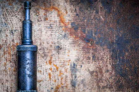 Color image of a grease pump on a wooden plank.