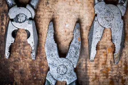 Color image of some pliers on a wooden plank.