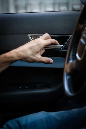 Close up image a hand opening a car door from inside.