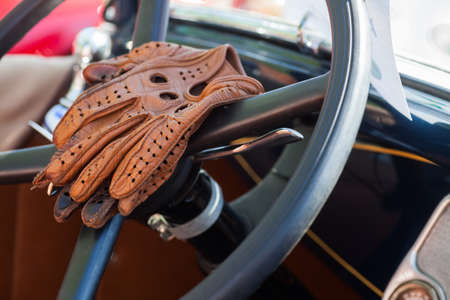 Color image of some vintage leather gloves on a car's steering wheel.