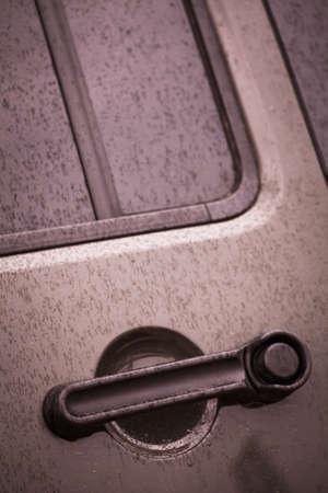 Color image of a car door handle, with rain drops.