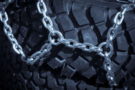 Close up shot of some chains wrapped around a car's tire.の写真素材