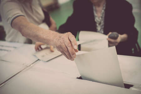 Hand of a person casting a ballot at a polling station during voting.の写真素材