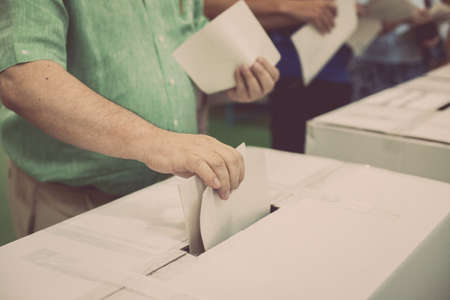 Hand of a person casting a ballot at a polling station during voting.の写真素材