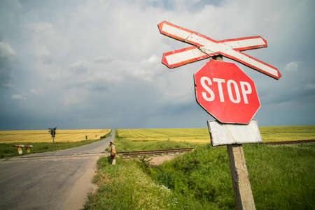 Color image of a stop sign at a railway crossing, on a cloudy day.の写真素材