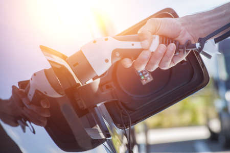 Color image of a man's hand preparing to charge an electric car.の写真素材