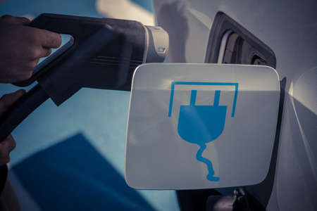 Color image of a man's hand preparing to charge an electric car.の写真素材
