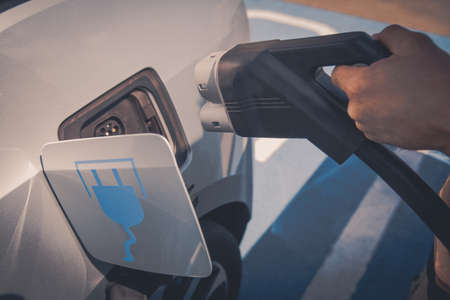 Color image of a man's hand preparing to charge an electric car.の写真素材