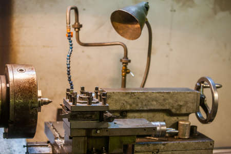 Color image of an old lathe in a workshop.