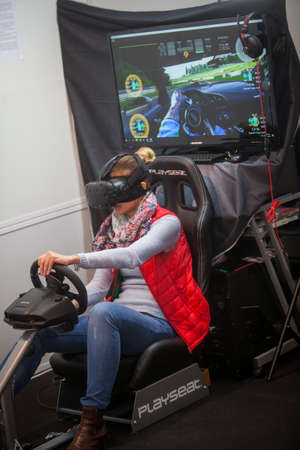 Bucharest, Romania - October 26, 2016: A woman is playing a driving game with virtual reality gear...