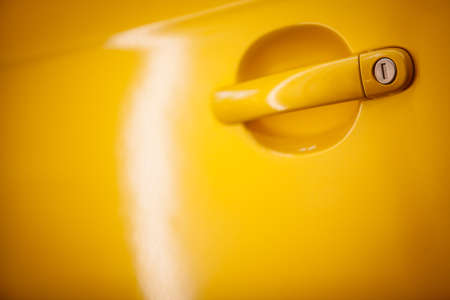 Close up shot of a yellow car's door handle.