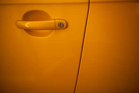 Close up shot of a yellow car's door handle.