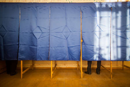 People vote in a voting booth at a polling station.の写真素材