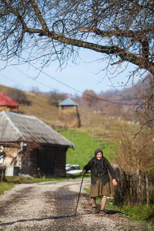 Breb, Romania - November 18, 2016: An elderly woman walks down a street in Breb, Maramures, Romania.のeditorial素材