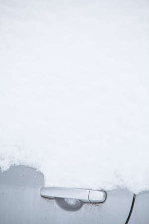 Color image of a parked car door handle, under heavy snow.の写真素材