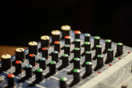 Close up shot of a mixer desk with many buttons.